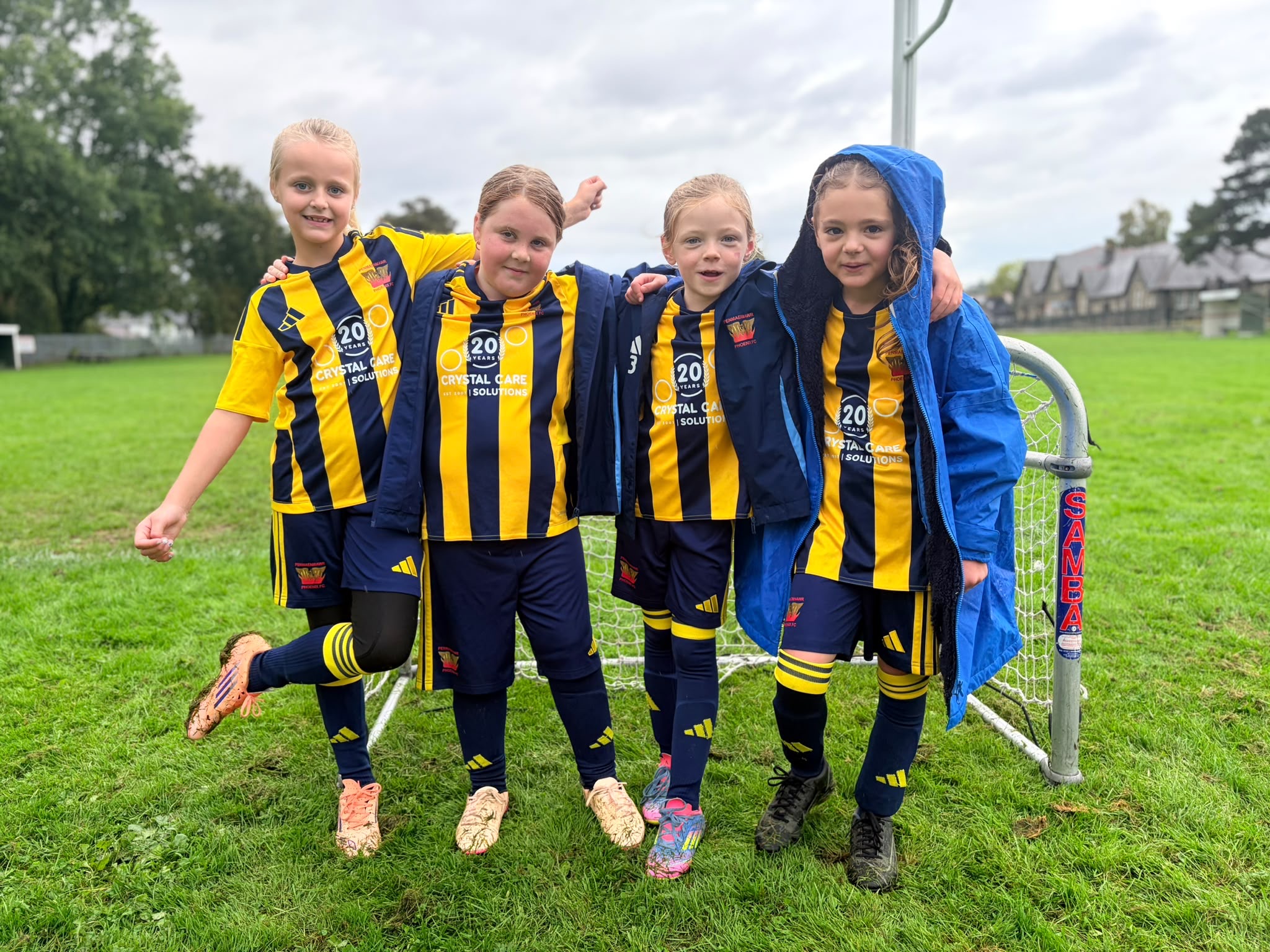 Four U8 Girls Yellow players together beside the goal